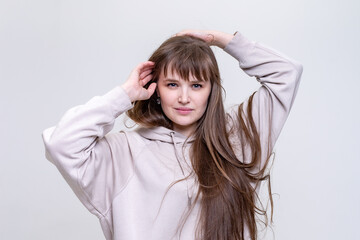 Fototapeta premium portrait of a pretty blonde girl with long hair in a beige hoodie on a light background
