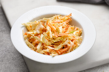 Cole slow salad with white cabbage and carrots. Coleslaw salad with carrot and cabbage on a white bowl.