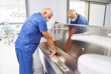 Älterer Chirurg beim Händewaschen zur Desinfektion
