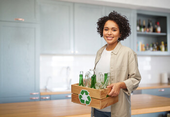 recycling, waste sorting and sustainability concept - happy smiling woman holding wooden box with glass bottles over home kitchen background