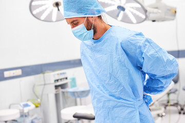 Chirurg mit Mundschutz beim Kittel anziehen vor der OP