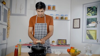 Indian home chef putting instant noodles in a pan - quick meal concept. Wide shot of an attractive man alone at the house making delicious Chinese food - home cooking concept.