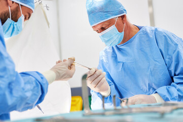 Assistenzarzt gibt Oberarzt ein chirurgisches Instrument