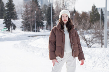 Portrait of a young beautiful girl in a brown down jacket 