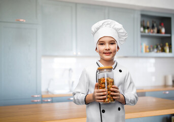 cooking, culinary and profession concept - happy smiling little boy in chef's toque and jacket holding jar with pasta over kitchen background