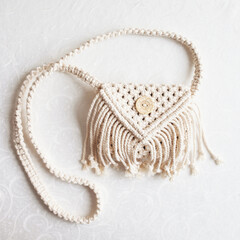 Handmade white macrame bag on the linen background, ECO friendly. Hobby knitting handmade macrame. Modern summer concept. Copy space