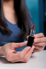 Close up of social media influencer holding lipstick while recording make up review for vlogging channel in studio. Blogger content creator filming cosmetics tutorial advertising product