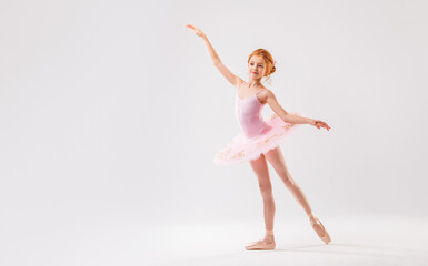 Naklejka na ściany i meble Little ballerina dancer in a pink tutu academy student posing on a white background