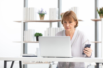 senior businesswoman or freelancer looking smartphone for checking something for work