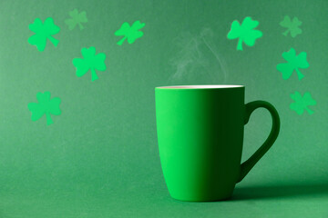Patricks day celebration with cozy green coffee or tea mug on green background. Space for text....