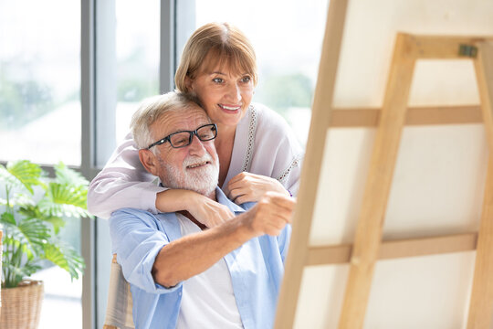 senior couple looking to painting on a canvas in free time