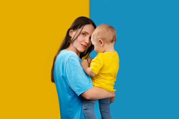 YOUNG MOTHER WITH HER CHILD IN THE COLORS OF UKRAINE - 492758336