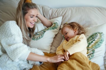 Young beautiful mother playing with baby daughter at home.