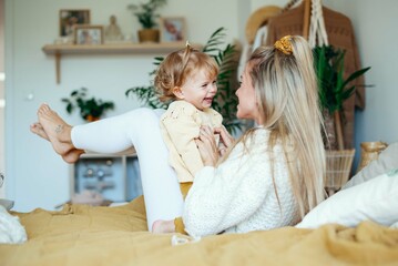 Young beautiful mother playing with baby daughter at home. © therabbithole