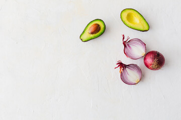 Overhead view avocado and red onion on white background