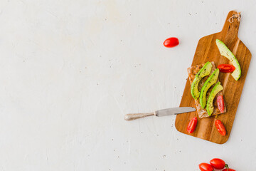 Overhead view with healthy toasts with avocado and tomato on wooden board on white background