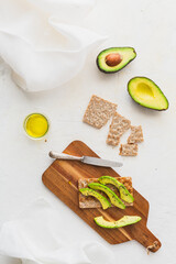 Overhead view with healthy toasts with avocado on wooden board on white background