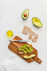 Overhead view with healthy toasts with avocado and linen napkin on wooden board on white background