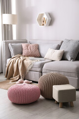 Stylish poufs and ottoman near sofa in living room. Interior element