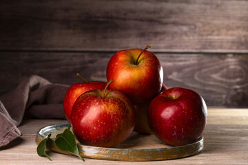 Fresh apples on a plate on a wood background.