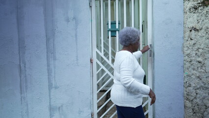Obraz na płótnie Canvas An African woman arriving home opening door entrance a black lady