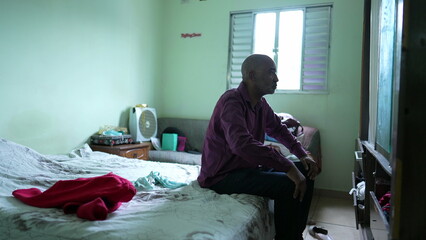 A thoughtful African man in bedroom thinking about life during middle life 50s