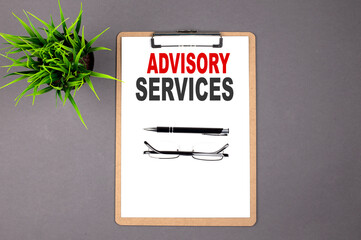 Text ADVISORY SERVICES on brown clipboard on the grey background. Business concept