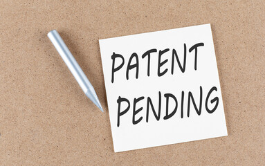 PATENT PENDING text on sticky note on cork board with pencil ,