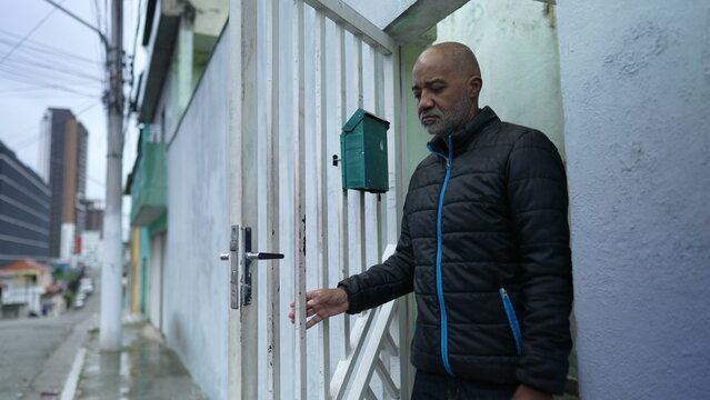 A Senior Man Stepping Outside In Street Opening Front Door