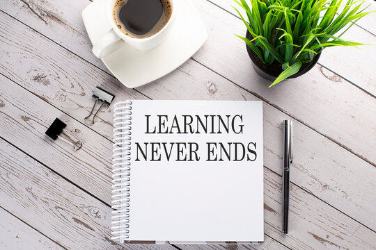 Cofee cup, notepad,pen on the wooden background. Business concept. Text LEARNING NEVER ENDS