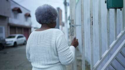 A senior black woman leaving house person opening front door