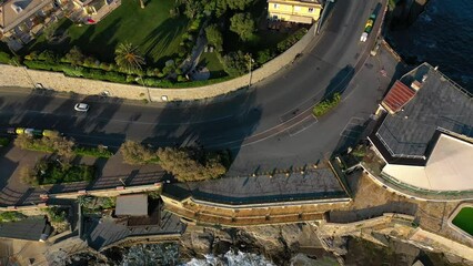 Aerial view of traffic on a coastal road, revealing the cityscape of east Genova,, Italy - reverse, tilt, drone shot