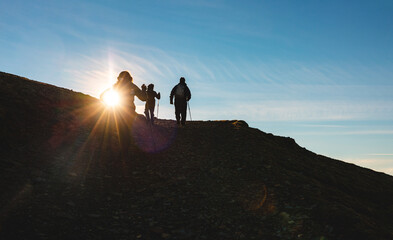 People hiking on mountain at sunset and walking toward the top