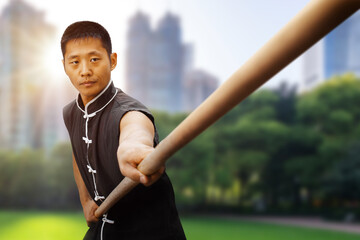 Wushu practice outdoors. Fighter with a stick in his hands