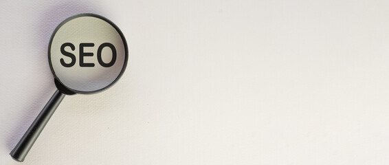 SEO or Search Engine Optimization concept.,magnifying glass with text SEO over white wall background with copyspace for put your text or logo.