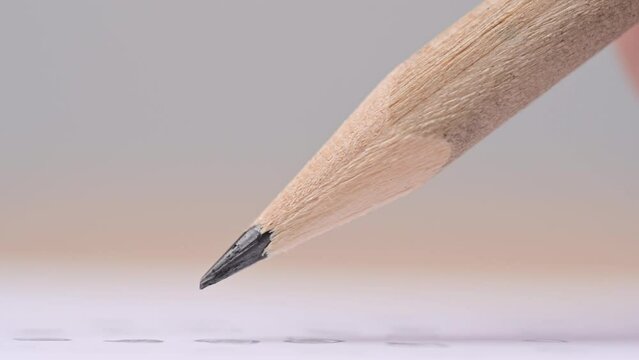 Macro of pencil writing or drawing. Unknown person drawing line or letter on white paper.
