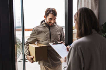 shipping, transportation and people concept - delivery man with parcel box and customer signing...
