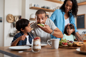 The boy just cant resist a good breakfast. Shot of a family of four enjoying breakfast together at...