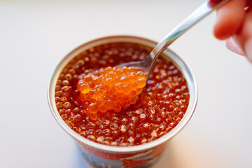 a spoonful of salted red caviar is taken out of the jar. delicacy. delicious canned fish. a traditional Russian snack for a festive banquet.