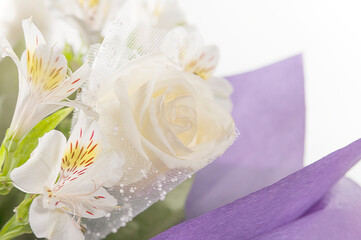 Bouquet of flowers in a purple wrapper close-up..White roses and white alstroemeria in a luxurious bouquet.