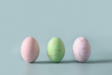 Three decorative pastel eggs on blue background. Happy Easter greeting card with copy space.