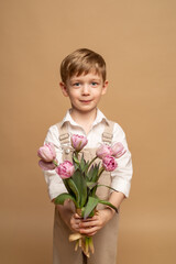 charming blonde four-year-old boy holds a bouquet of pink tulips