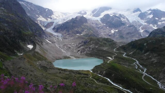 Aerial flyover towards the heart shaped lake and glacier Stein at Sustenpass, Switzerland with a view of tall peaks of the Swiss Alps at twilight