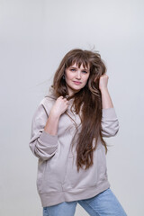 Fototapeta premium portrait of a pretty blonde girl with long hair in a beige hoodie on a light background