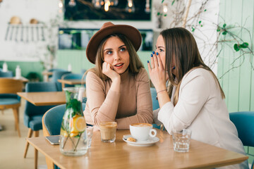 women whispers on coffee break in cafeteria