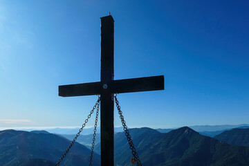 A wooden cross on top of Hohe Weichsel, Alpine peak in Austria. The cross is supported by 4 metal...