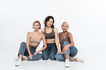 Fototapeta na wymiar Women in tops and jeans looking at camera on grey background.