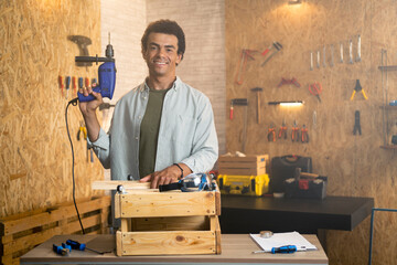 Portrait of a smiling carpenter in workshop with a drill