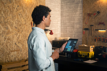 Carpenter in workshop holding and looking at tablet