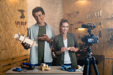 Two people in a carpentry workshop being filmed with a camera for a blog. Focus is on camera.